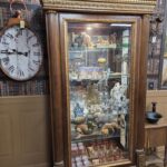 Victorian Neoclassical display cabinet with gilt detailing, fluted columns, and beveled glass doors, antique wood showcase furniture.