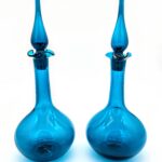 Pair of mid-century blue glass decanters with teardrop stoppers and sculptural silhouettes.