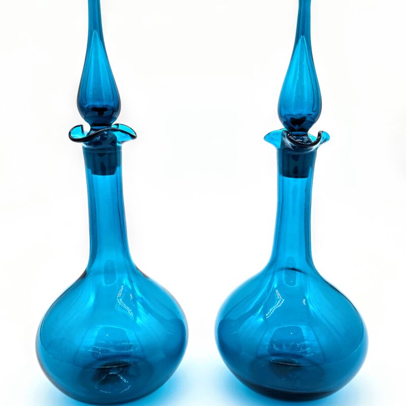 Pair of mid-century blue glass decanters with teardrop stoppers and sculptural silhouettes.