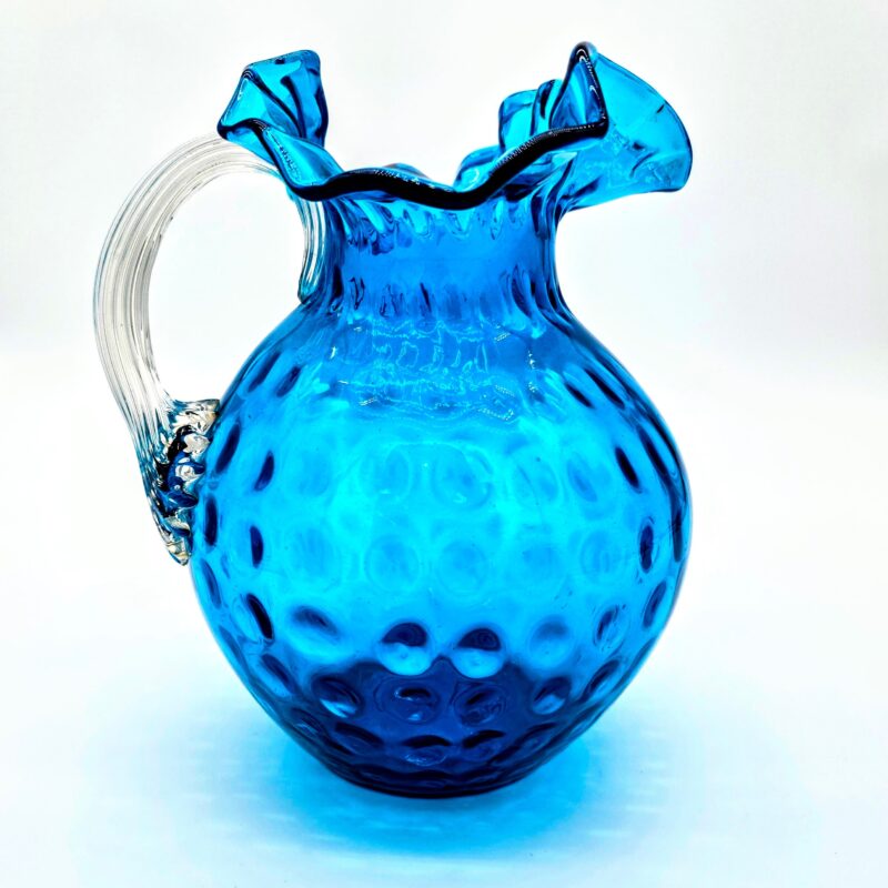 Fenton blue hobnail glass pitcher with ruffled rim and clear ribbed handle.