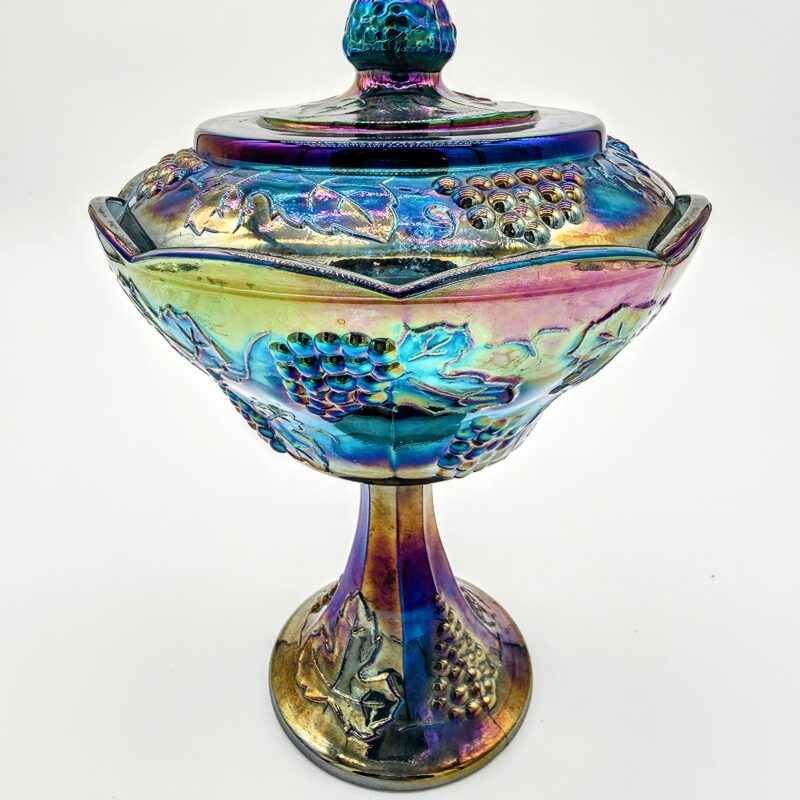 Blue carnival glass candy dish with lid and pedestal base featuring grape and leaf pattern.