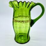 Vintage green glass pitcher with ruffled rim and gold painted band detailing.