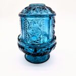 Vintage blue pressed glass fairy light with starburst pattern and pedestal base.