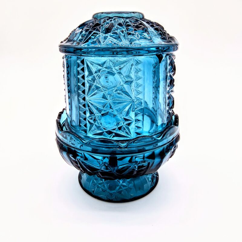Vintage blue pressed glass fairy light with starburst pattern and pedestal base.