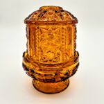 Vintage amber-orange pressed glass fairy light with starburst pattern and pedestal base.
