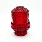 Vintage red pressed glass fairy light with starburst pattern and pedestal base.