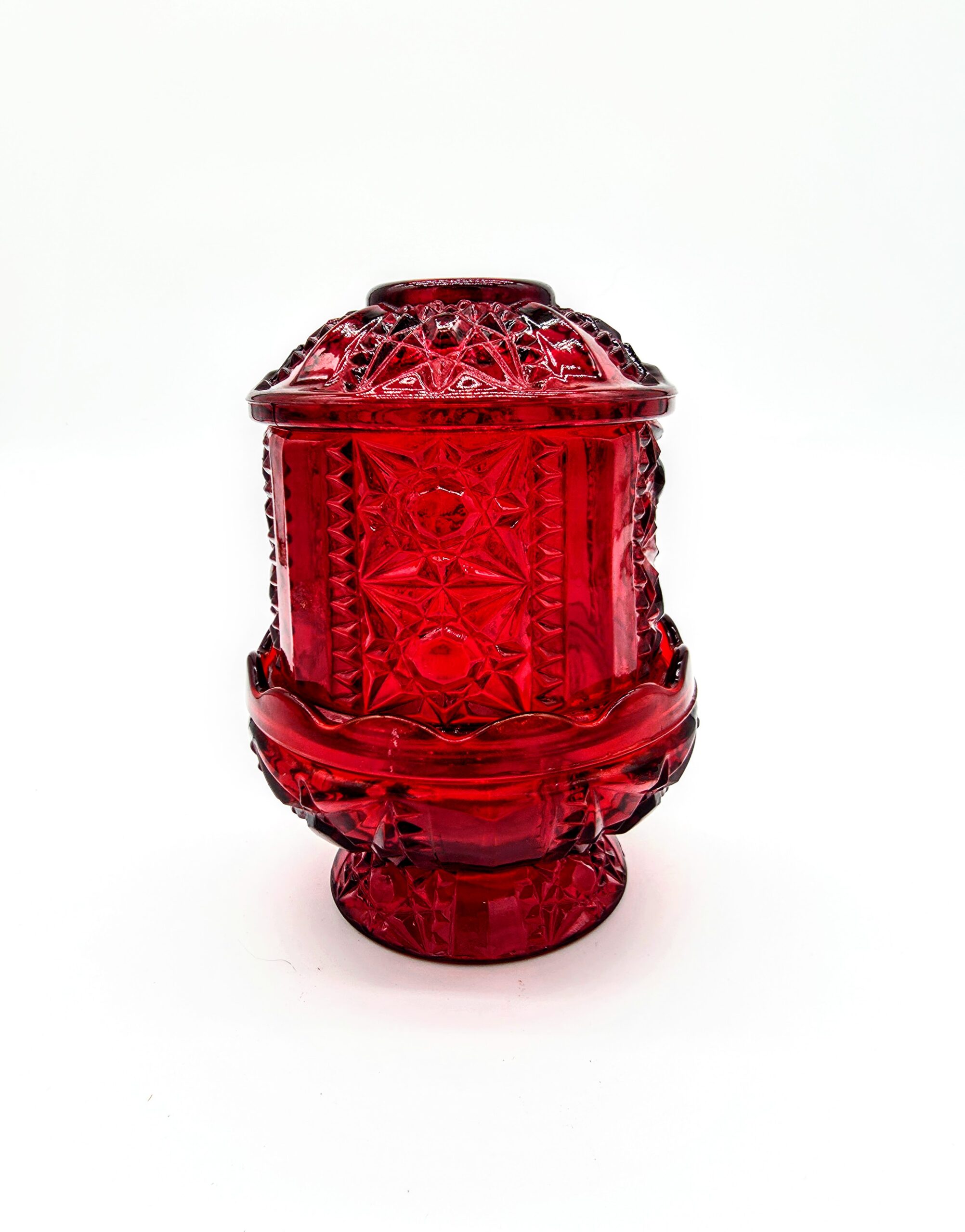 Vintage red pressed glass fairy light with starburst pattern and pedestal base.