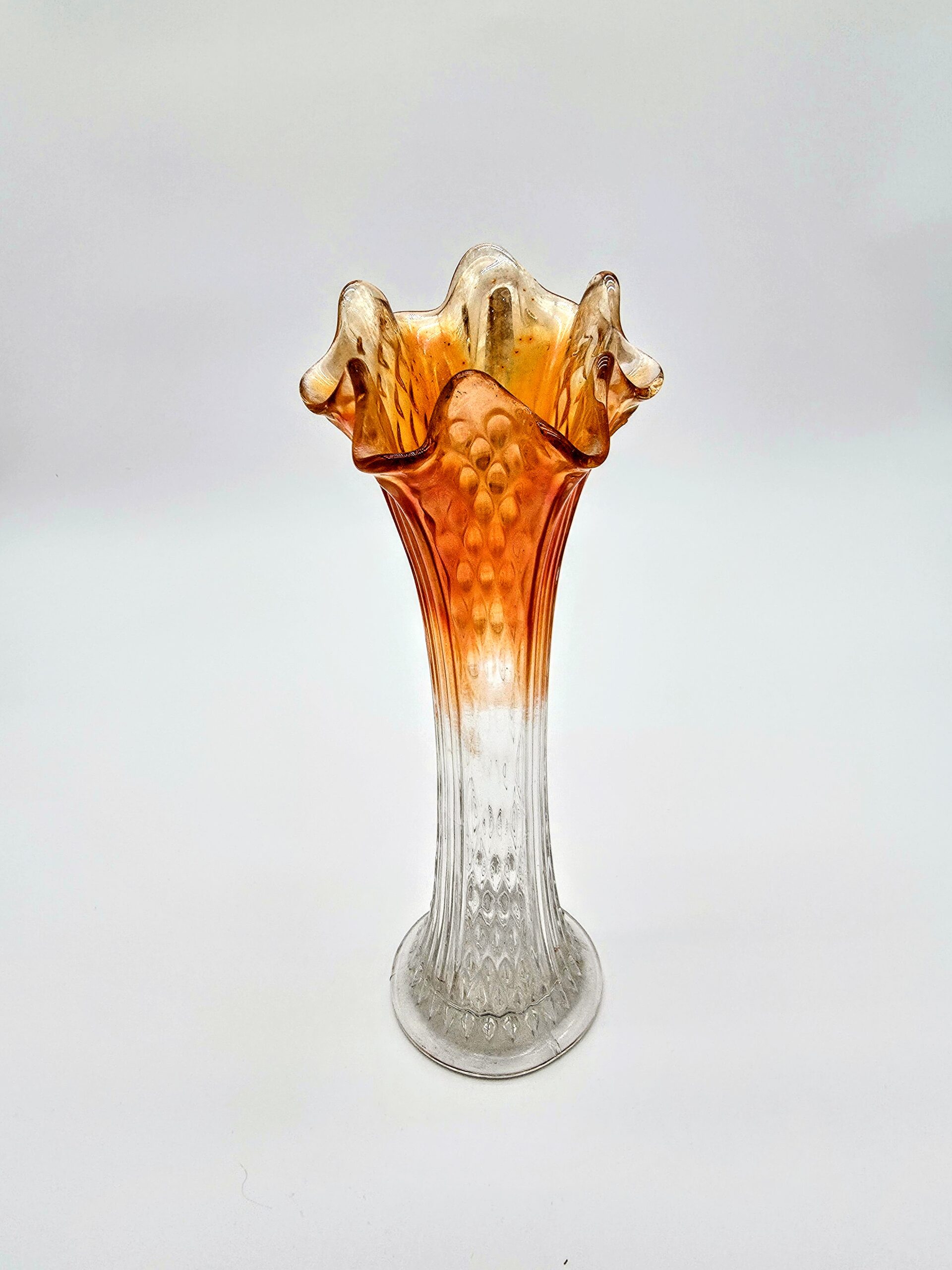 Orange fluted glass vase with hobnail texture and ruffled rim transitioning from clear to amber.