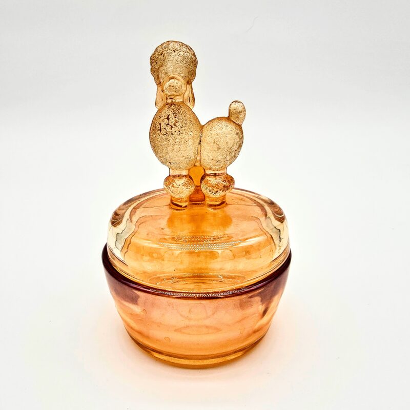 Vintage orange pressed glass candy dish with poodle-shaped lid and iridescent amber tone.