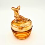 Vintage orange pressed glass candy dish with dog-shaped lid and smooth amber finish.