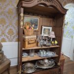 Vintage ornate display cabinet with carved wood details, curved glass panels, and mirrored interior — classic antique showcase furniture.