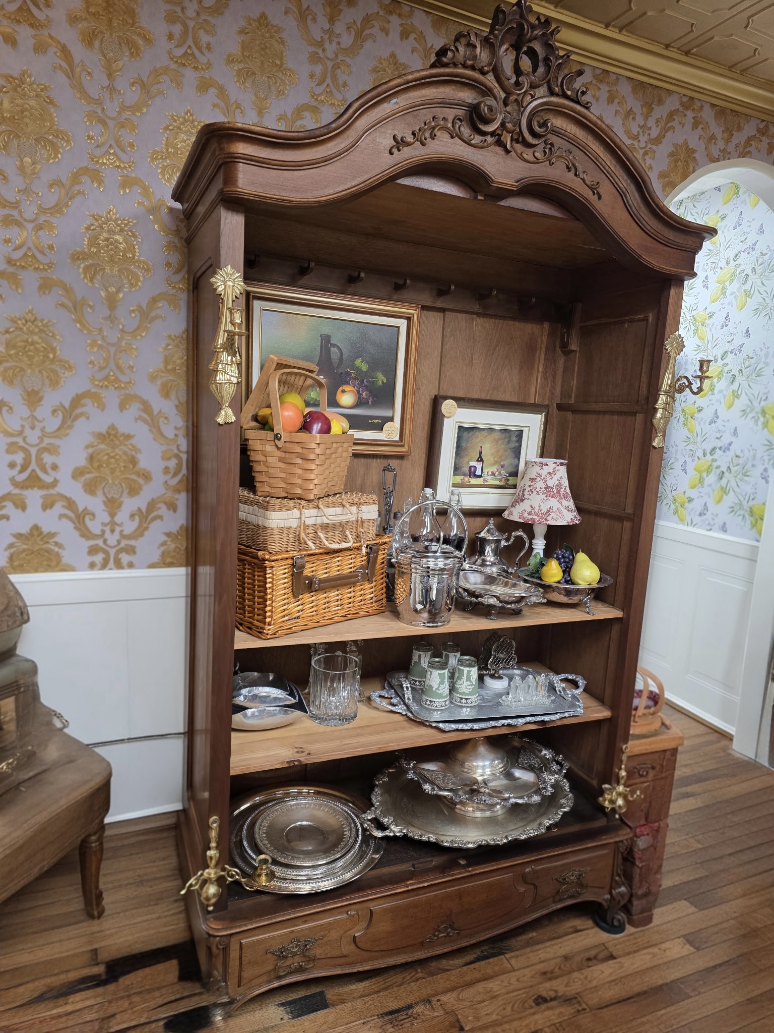 Vintage ornate display cabinet with carved wood details, curved glass panels, and mirrored interior — classic antique showcase furniture.